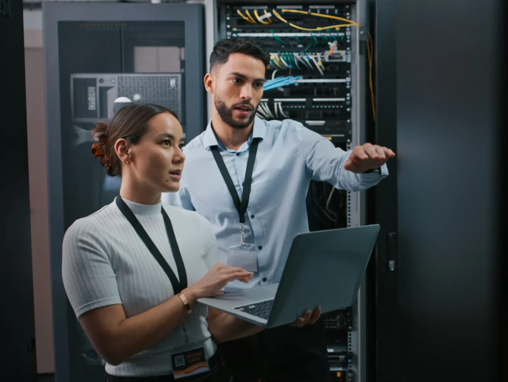 An image of two people holding a laptop and providing managed IT services.